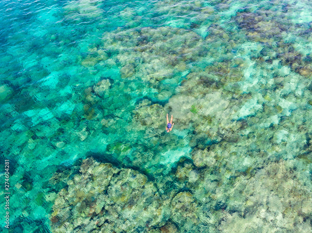 Fototapeta premium Aerial top down people snorkeling on coral reef tropical caribbean sea, turquoise blue water. Indonesia Wakatobi archipelago, marine national park, tourist diving travel destination