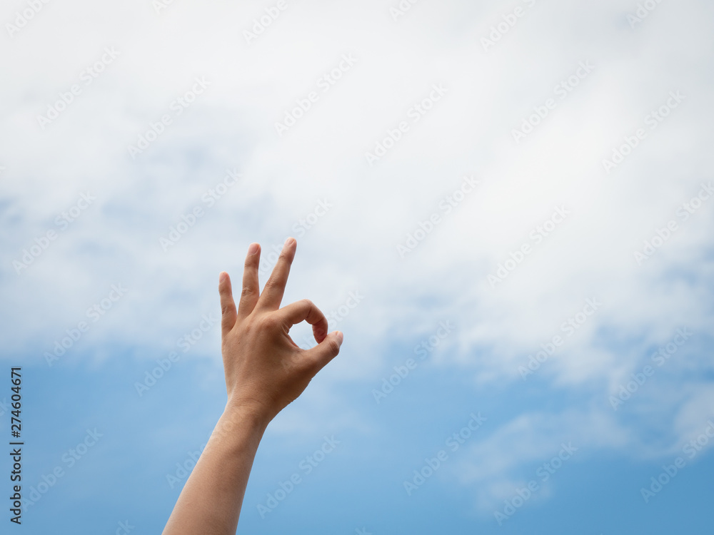 Okey. Woman hand OK sign against with blue sky and white clouds. Okey. Woman hand OK sign against with blue sky and white clouds.