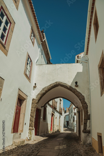 Old whitewashed houses in alley and passageway under arch