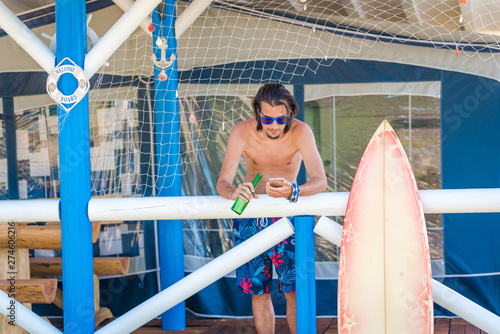 Young attractive man surfer  looking at his smartphoe. Caravan camping. Summer vacation recreation photo. photo