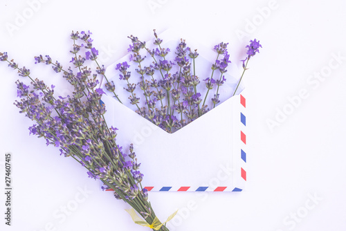 Fresh lavender bouquet and blank airmail envelope isolated on white background. Romantic message concept with copy space. Flat lay.