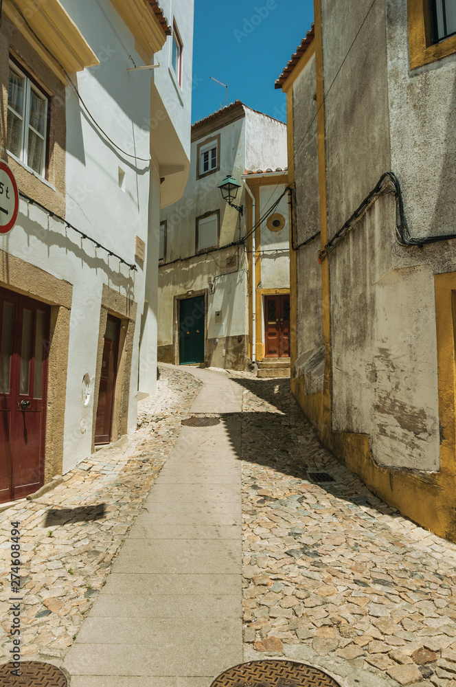 Old houses with whitewashed wall in cobblestone alley