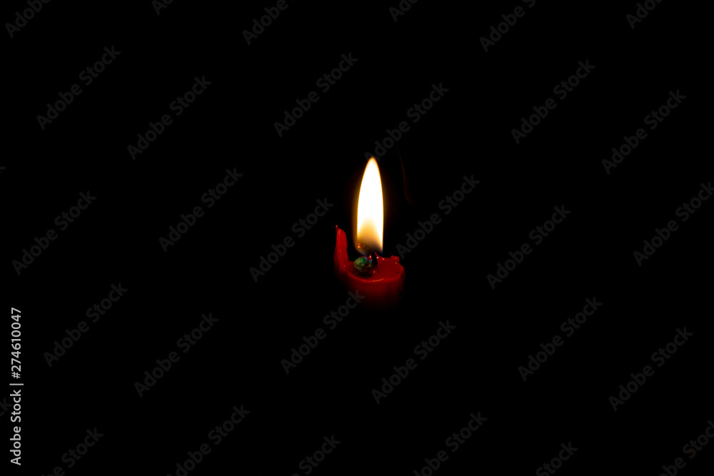 Fototapeta premium Light from the candle flame isolated on dark background