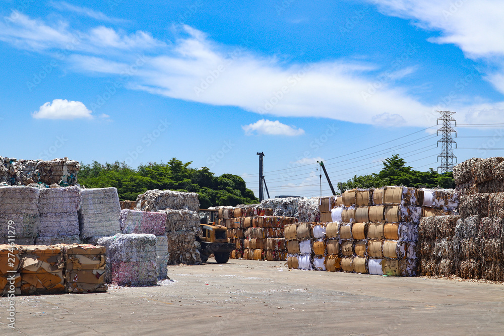 Fototapeta premium Bangkok/Thailand-June 22,2019: Thai recycle industry cardboard garbage and paper waste after pressing in hydraulic baling garbage press machine to a square dense for transportation to recycle factory