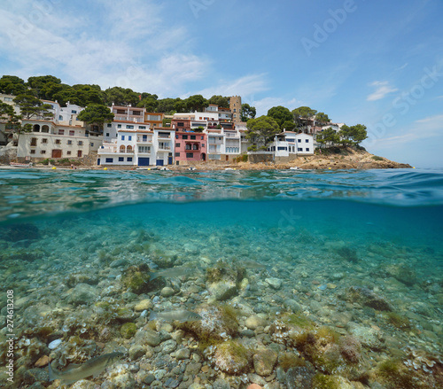 Coastline of Mediterranean village on Costa Brava in Spain with sea bass fish and rocks underwater, Sa Tuna, Begur, Catalonia, split view over and under water