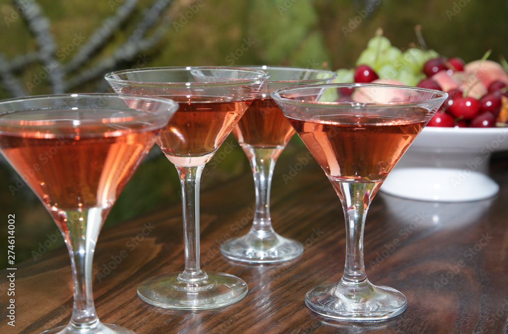 Obraz premium martini glasses of red wine cocktail on a wooden table of a fruit bar in a soft blurred background