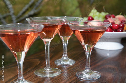  martini glasses of red wine cocktail on a wooden table of a fruit bar in a soft blurred background