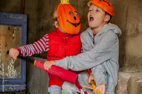 Caucasian boys in pumpkin masks and carnival clothes fight each other with help of sword and baton. Children are happy together. halloween eve