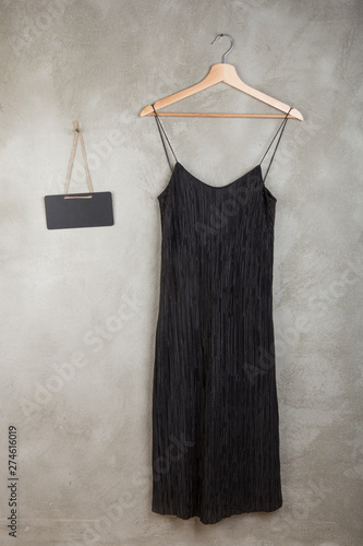 Fashion and shopping concept - blank blackboard and beautiful black dress on a hanger