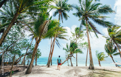 Man standing on the beach and enjoying the tropical place with a view. caribbean sea colors and palm trees in the background. Concept about travels and lifestyle