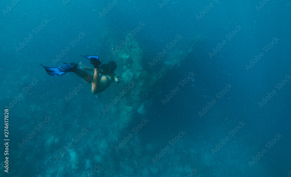 Discovering a japanese ship wreck from second world war. Beautiful woman swimming underwater in a tropical sea. under water shot with action camera. concept about wanderlust travels Discovering a japanese ship wreck from second world war. Beautiful woman swimming underwater in a tropical sea. under water shot with action camera. concept about wanderlust travels