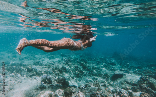 Woman swimming underwater. Concept about vacations and nature. Shot taken with under water action camera