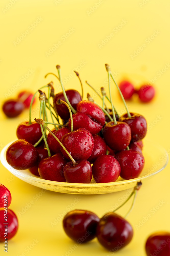Freshly picked cherries in a glass bowl. Bright yellow background, water drops, high resolution Freshly picked cherries in a glass bowl. Bright yellow background, water drops, high resolution