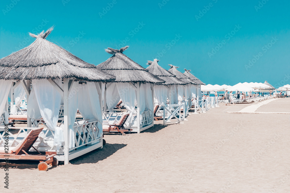White tents and umbrellas on the sandy shore with magical beauty blue sky