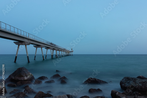 Long exposure of the oil bridge in Badalona at sunset  with people walking in motion