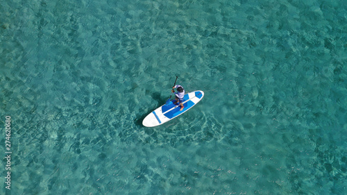 Aerial photo of unidentified fit man practising SUP or Stand Up Paddle in tropical exotic destination island with turquoise sea © aerial-drone