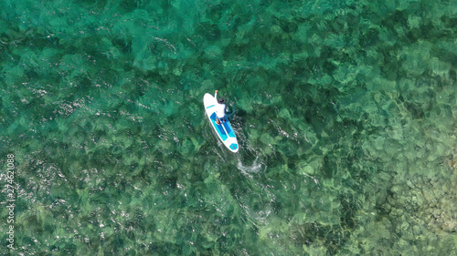 Aerial drone photo of unidentified fit man practising Stand Up Paddle or SUP in tropical exotic mediterranean bay with turquoise sea