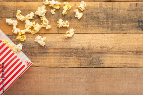 packaging with popcorn on a wooden background. sprinkled popcorn. rest and entertainment. background