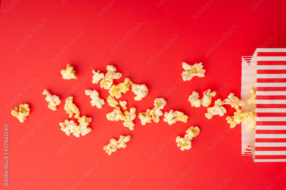 Popcorn packaging on a bright red background. sprinkled popcorn. rest and entertainment. Flat lay Popcorn packaging on a bright red background. sprinkled popcorn. rest and entertainment. Flat lay