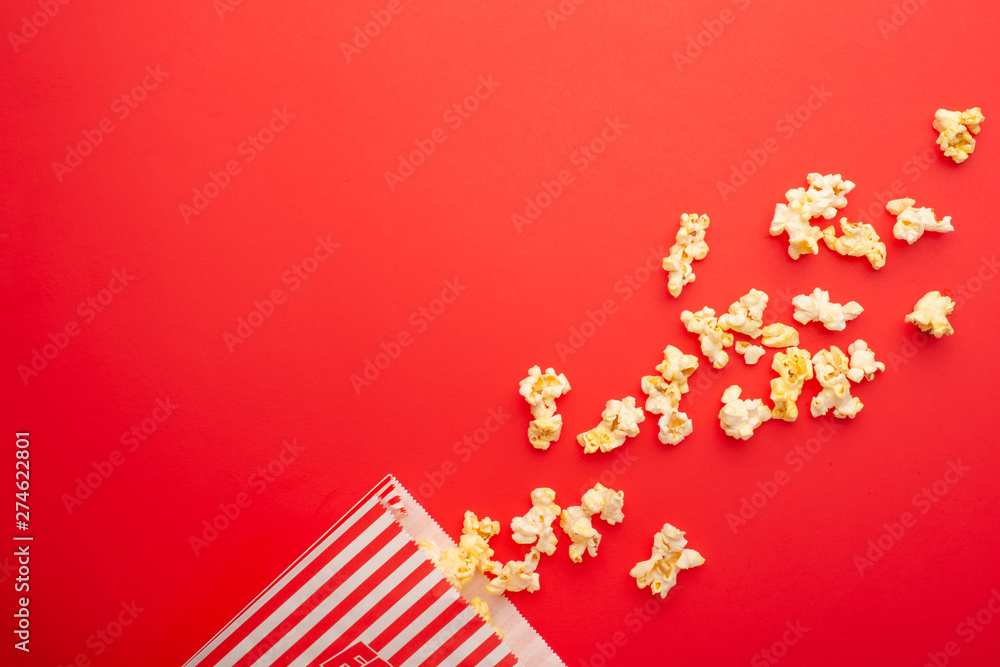 Popcorn packaging on a bright red background. sprinkled popcorn. rest and entertainment. Flat lay