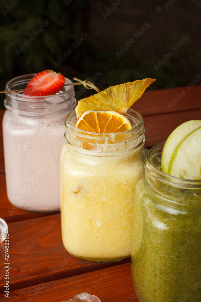 Close up view of different tastes of smoothies on a wooden table: strawberry, apple green, citrus and berries smoothies Close up view of different tastes of smoothies on a wooden table: strawberry, apple green, citrus and berries smoothies
