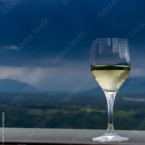 A glass of white whine with mountains in the background and approaching rain