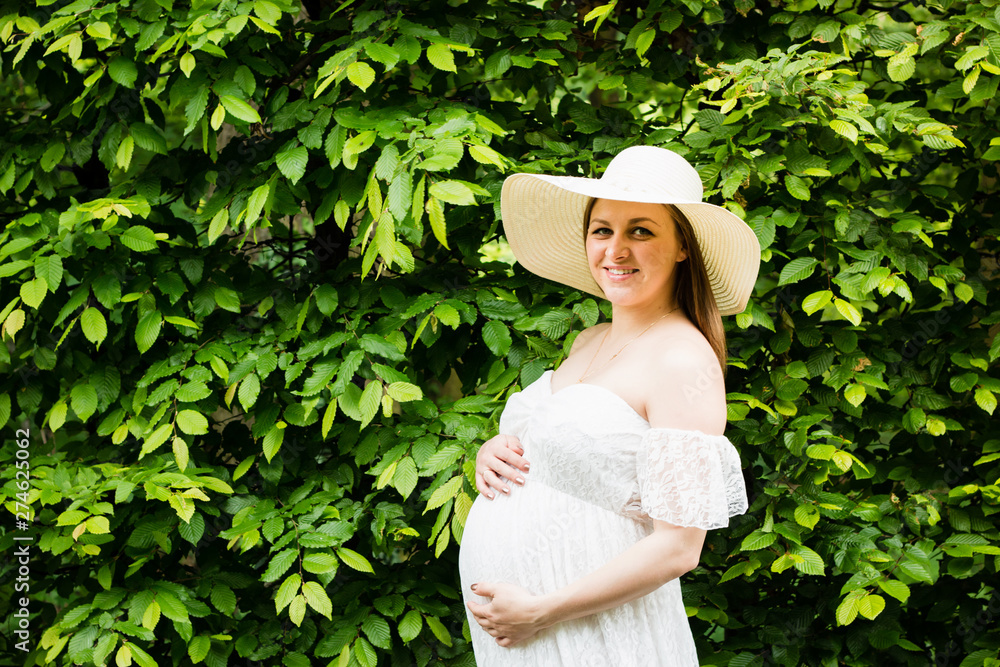 Happy pregnant woman posing over green natural background Happy pregnant woman posing over green natural background
