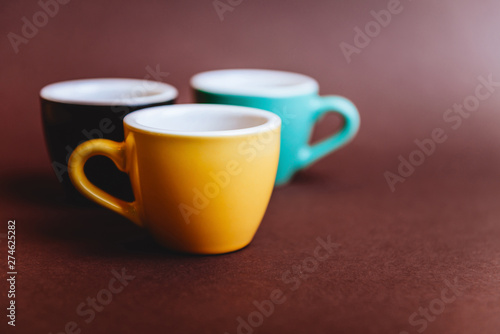 Threee colorfull cups of espresso coffee on dark background