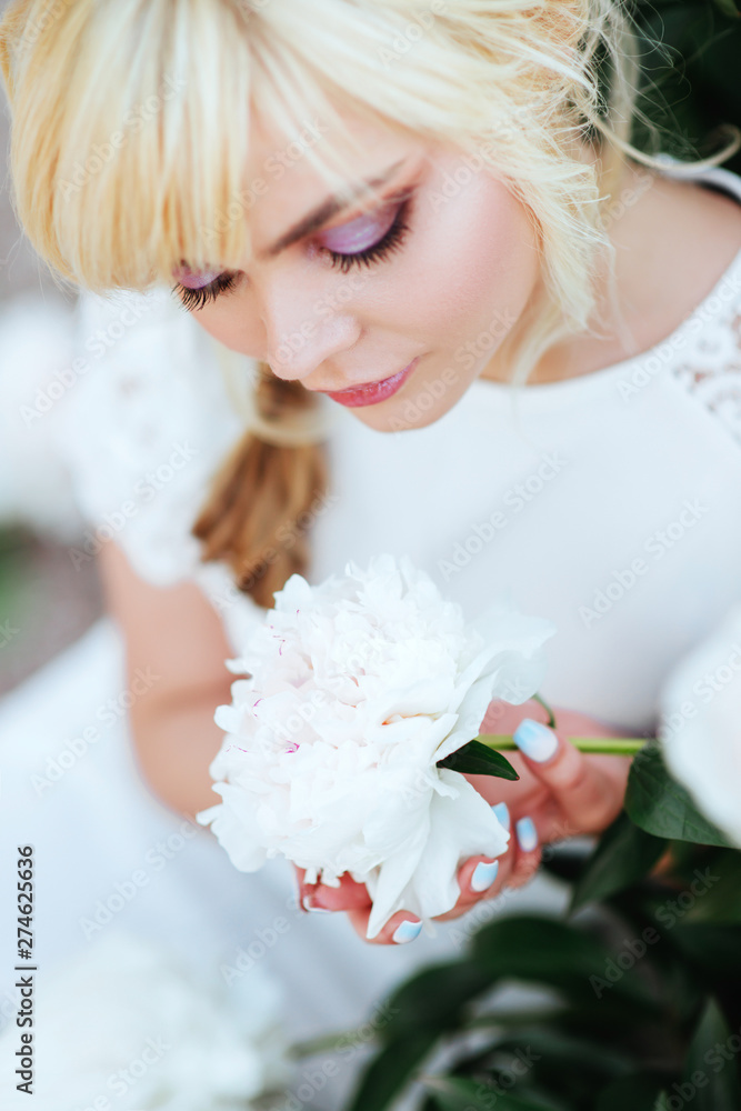 Outdoor close up portrait of beautiful young woman with long blonde hair, makeup, posing in the blooming garden. Female spring fashion concept Outdoor close up portrait of beautiful young woman with long blonde hair, makeup, posing in the blooming garden. Female spring fashion concept