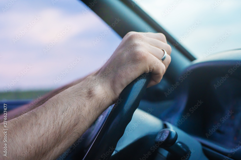 Close up side view shot of male hands on steering wheel while journey