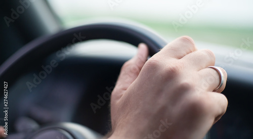 Close up side view shot of male hands on steering wheel while journey