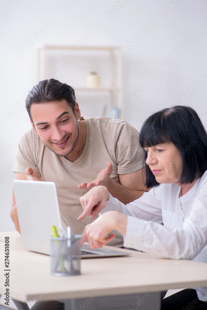 Young male employee explaining to old female colleague how to us Young male employee explaining to old female colleague how to us