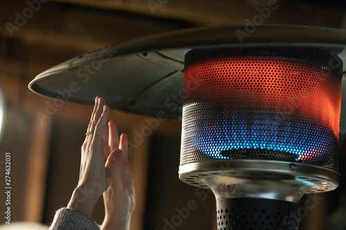 Hands warming close to the flames of propane patio heater