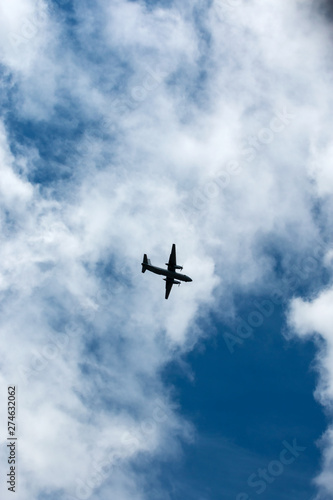 the plane flies across the blue sky