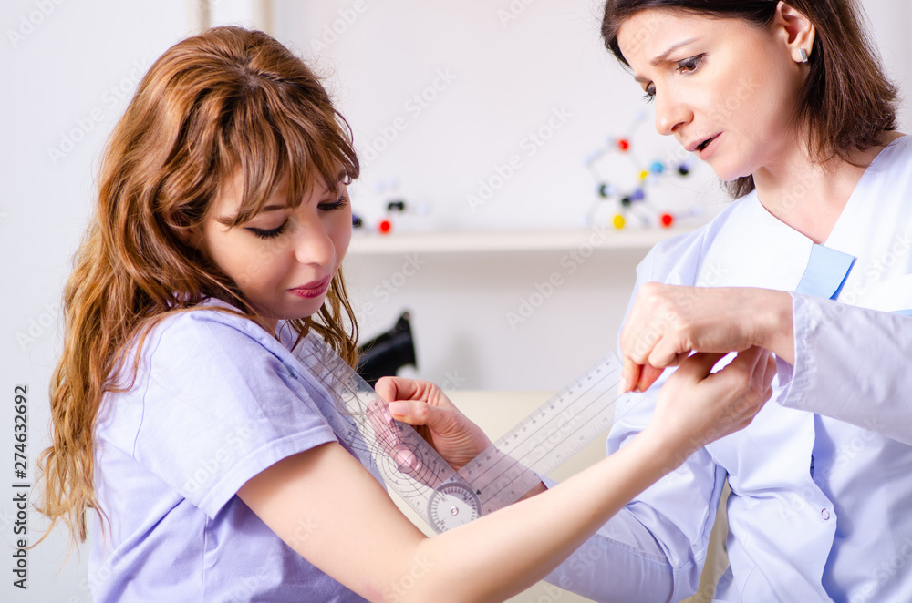Female doctor checking patient's joint flexibility with goniomet Female doctor checking patient's joint flexibility with goniomet