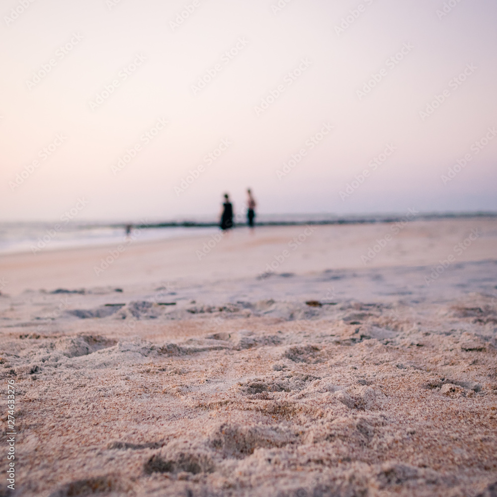 Two People Walking on the Beach Waiting for Sunrise