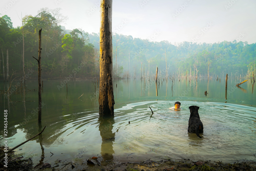 Obraz premium Man and dog playing and swimming in a lake.