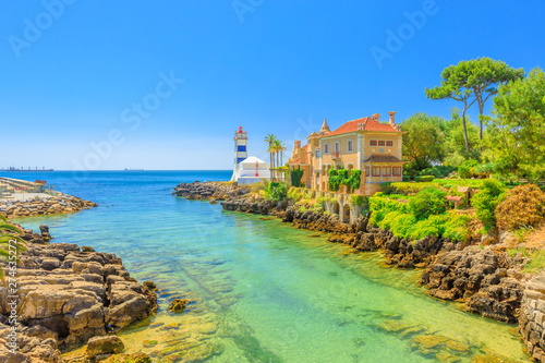 Scenic landscape of Santa Marta Lighthouse or Saint Martha's Lighthouse and House of Saint Mary or Casa de Santa Maria on Tagus River estuary in Cascais, Lisbon Coast, Portugal. Copy space. Blue sky.