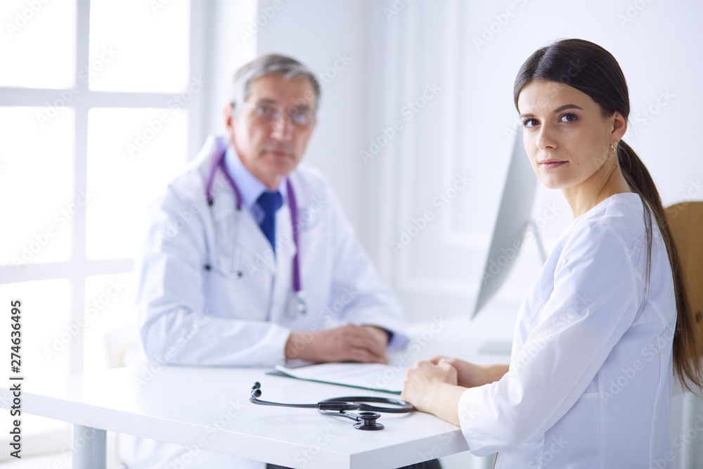 Two doctors smiling in consulting room in hospital Two doctors smiling in consulting room in hospital