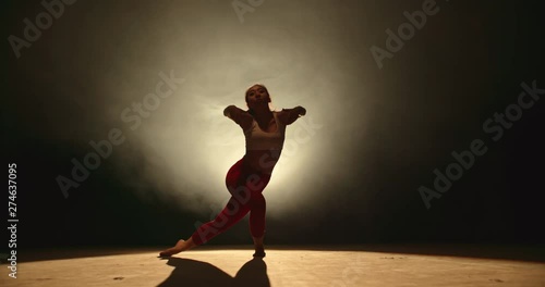 Asian girl perfoming contemporary dance on stage. Talented choreographist making creative dance show, spotted by white light on black background 4k footage photo