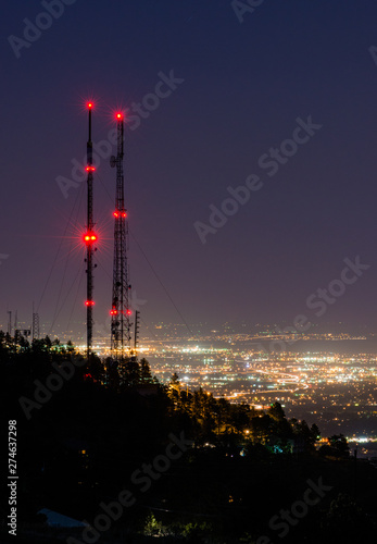 Antenna Towers on a hill over a brilliantly lit city at night