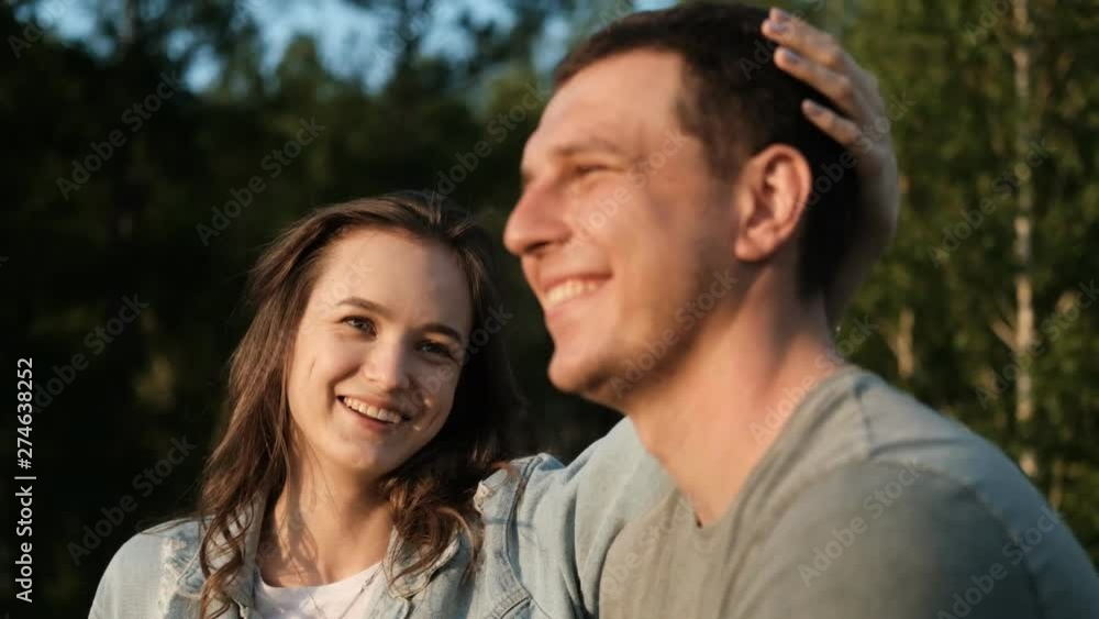 A young attractive woman strokes her boyfriend's head and smiles. A young attractive woman strokes her boyfriend's head and smiles.