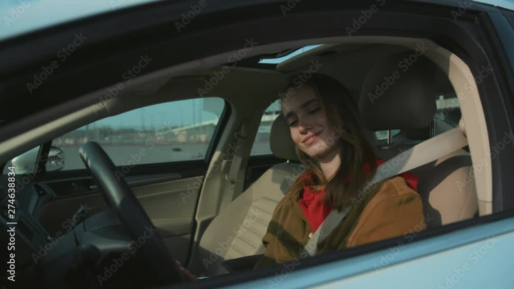 Cute young Caucasian woman in casual clothes at driver's seat. Shot of attractive brown-haired girl. Pretty driver after getting driver's license. Cute young Caucasian woman in casual clothes at driver's seat. Shot of attractive brown-haired girl. Pretty driver after getting driver's license.