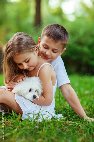 Children with a maltese puppy, outdoor summer