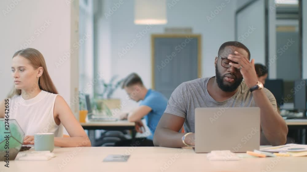 Young man reading bad news on laptop computer in office. Shocked african person Young man reading bad news on laptop computer in office. Shocked african person