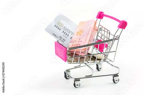 Credit cards and banknotes with thai currency coins in a small shopping cart on a white background.