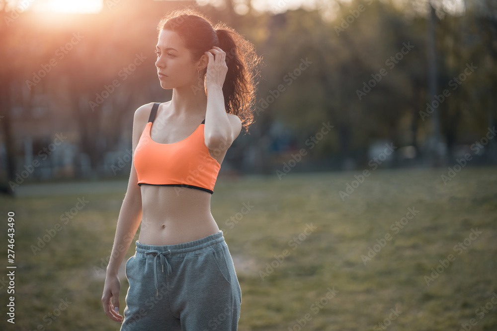 attractive brunette woman warm up and stretching in park at sunshine