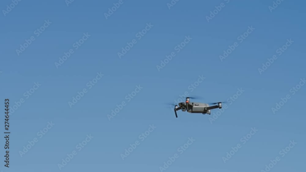 Unmanned small drone equipped video camera hovering in the air against a blue sky. Quadrocopter is flying, slow motion, close up 4k. Unmanned small drone equipped video camera hovering in the air against a blue sky. Quadrocopter is flying, slow motion, close up 4k.