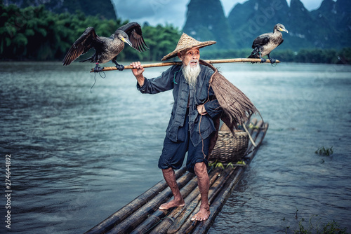 Cormorant fisherman in Traditional showing of his birds on Li river near Xingping, Guangxi province, China. photo