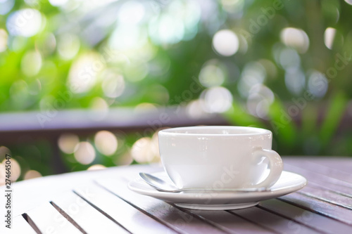 Closeup hot americano coffee on glass table with green nature background